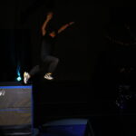 Un enfant effectue un saut acrobatique à partir d'une plateforme, sous des projecteurs qui éclairent la scène