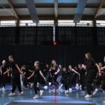 Un groupe d'enfants en tenues noires dansant synchroniquement sur scène