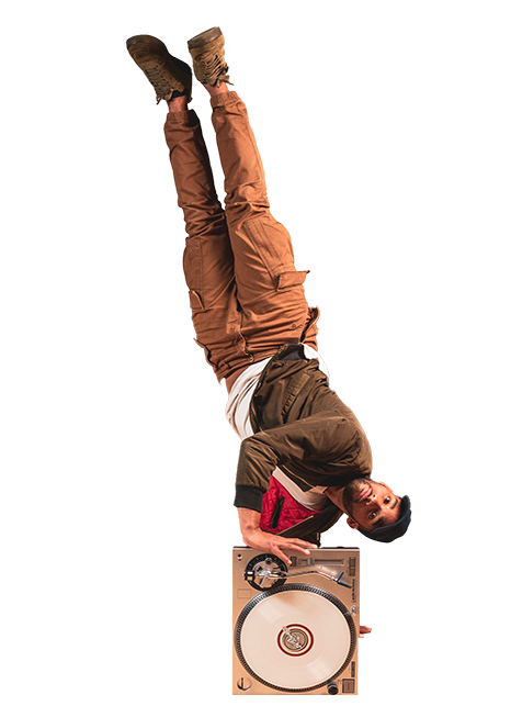 Un danseur effectue une figure acrobatique en équilibre sur ses mains, avec un tourne-disque placé au sol sous lui.